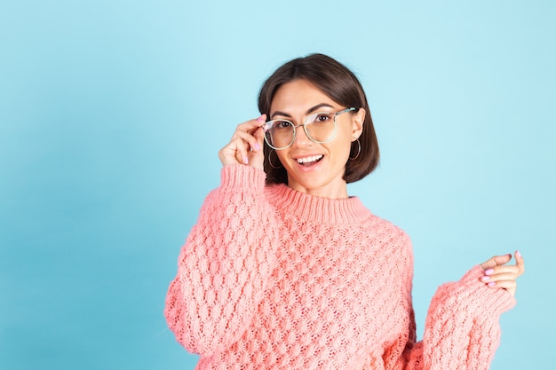 Junge Brünette im rosa Pullover lokalisiert auf blauer Wand