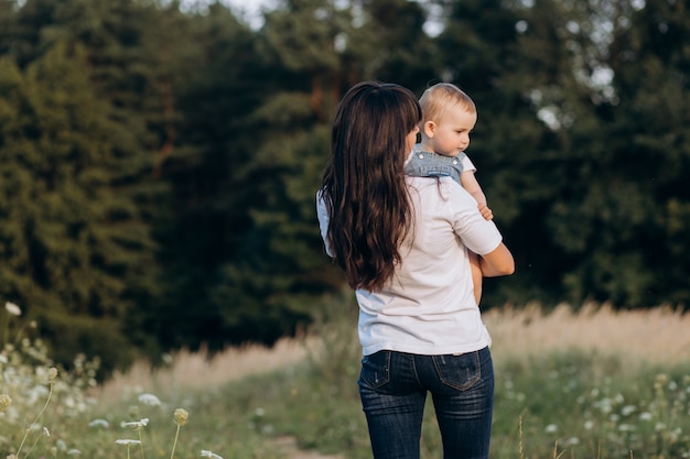 Junge Brünette Mutter geht mit ihrer kleinen Tochter über das Feld