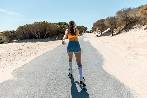 Junge Brunettefrau, die auf Asphaltstraße rollerblading ist