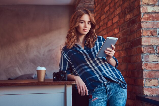 Junge charmante Fotografin, die mit einem Tablet in einem Gestüt arbeitet