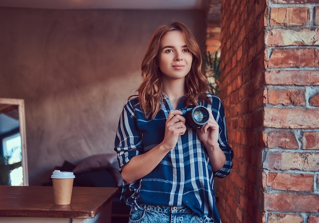 Kostenloses Foto junge charmante fotografin steht in einem raum mit dachboden