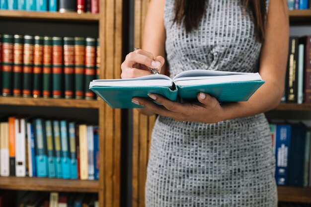 Junge Dame des Afroamerikaners mit Buch und Stift