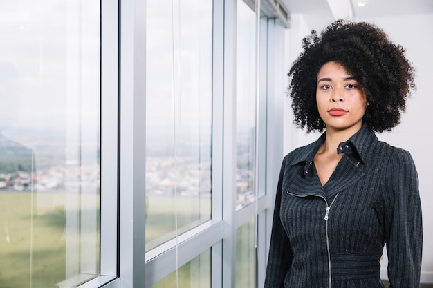 Junge Dame des Afroamerikaners nahe Fenster