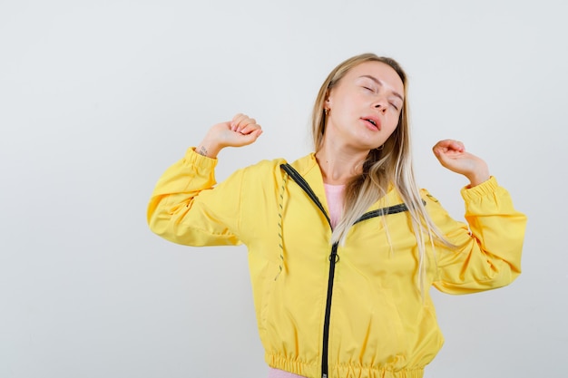 Junge Dame, die Arme in T-Shirt, Jacke streckt und schläfrig aussieht