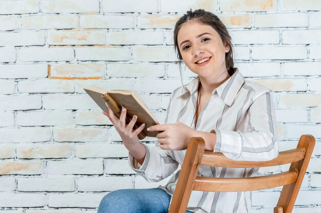 Junge Dame, die auf einem Stuhl sitzt und ihr Buch liest Foto in hoher Qualität