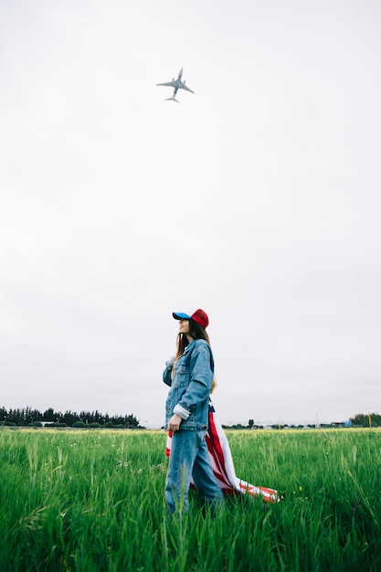 Junge Dame, die auf Gras und dem Lächeln bleibt