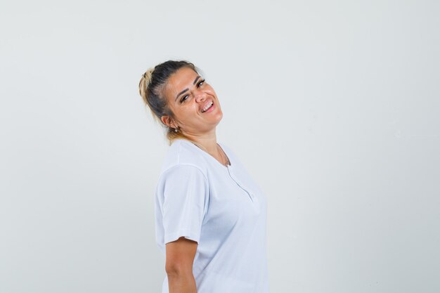 Junge Dame, die beim Stehen im T-Shirt aufwirft und selbstbewusst schaut