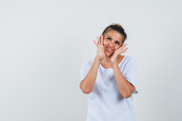 Junge Dame, die beim Stehen im T-Shirt aufwirft und zart schaut