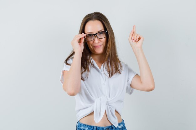 Junge Dame, die Brille trägt, während oben in der weißen Bluse, Vorderansicht zeigt.