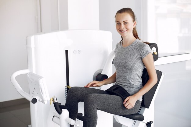 Junge Dame, die Übungen auf Simulator im Phisiotherapieraum macht