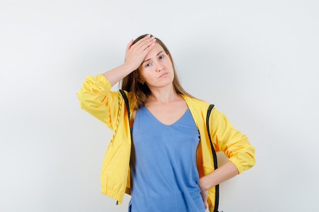 Junge Dame, die Hand auf der Stirn in T-Shirt, Jacke hält und nachdenklich schaut, Vorderansicht.