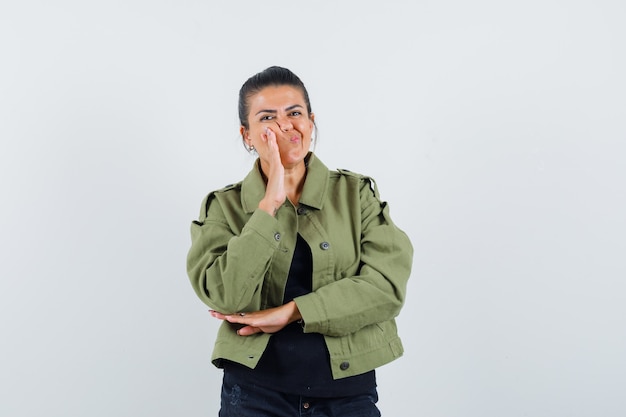 Junge Dame, die Hand auf Wange im T-Shirt hält