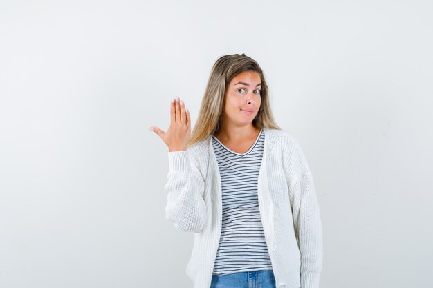 Junge Dame, die Hand im T-Shirt, in der Jacke anhebt und zuversichtlich schaut. Vorderansicht.