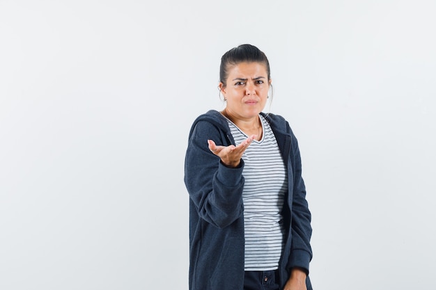 Junge Dame, die Hand in verwirrter Geste im T-Shirt streckt