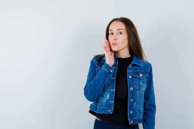 Junge Dame, die Haut auf ihrer Wange in Bluse, Jacke berührt und zart aussieht, Vorderansicht.