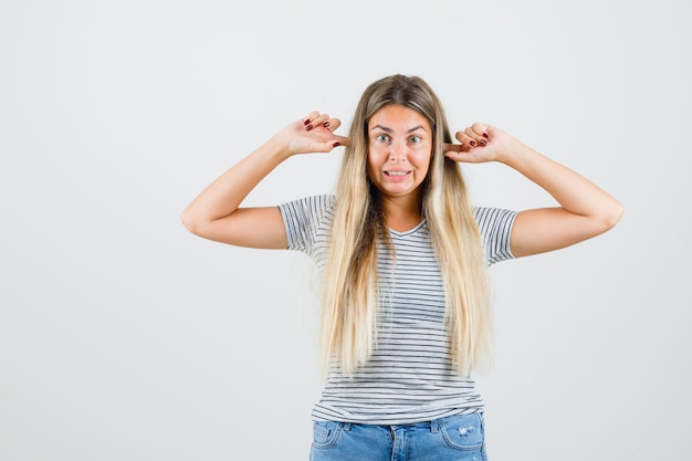 Kostenloses Foto junge dame, die ihre ohren in t-shirt einsteckt und gelangweilt, vorderansicht schaut.