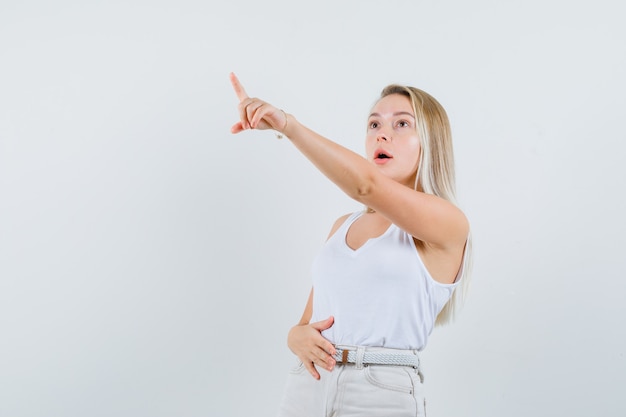 Kostenloses Foto junge dame, die in der weißen bluse weg zeigt und aufmerksam schaut