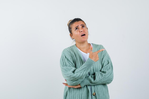 Junge Dame, die in T-Shirt, Jacke auf die rechte Seite zeigt und erstaunt aussieht