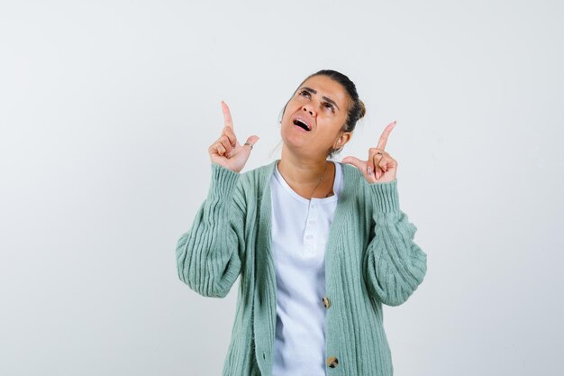 Junge Dame, die in T-Shirt, Jacke und nachdenklichem Blick nach oben zeigt