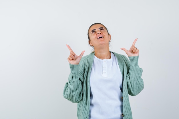 Junge Dame, die in T-Shirt und Jacke wegzeigt und erstaunt aussieht