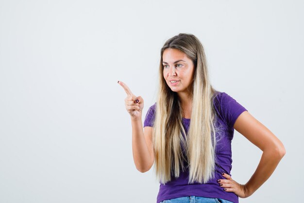 Junge Dame, die jemanden mit Finger im violetten T-Shirt warnt, Vorderansicht.