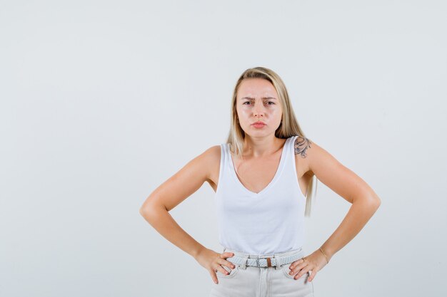 Junge Dame, die Kamera in der weißen Bluse betrachtet und unglücklich schaut