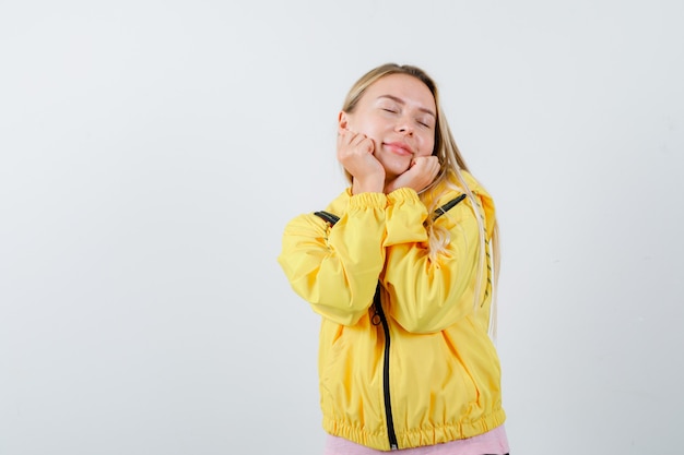 Junge Dame, die Kinn auf Hände im T-Shirt, in der Jacke lehnt und niedlich schaut