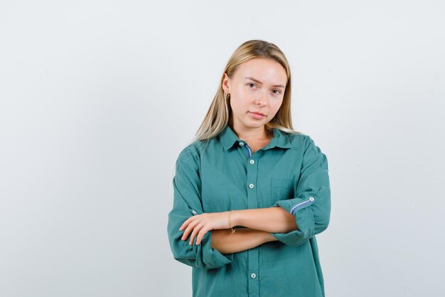 Junge Dame, die mit verschränkten Armen im grünen Hemd steht und selbstbewusst aussieht.