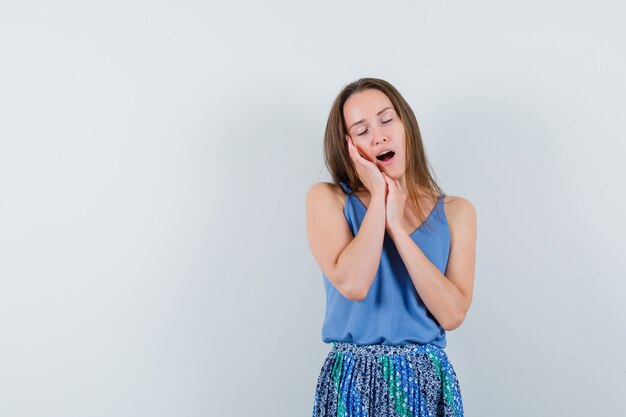 Junge Dame, die sich auf Handflächen als Kissen im Unterhemd, im Rock und in der entspannten Vorderansicht stützt.