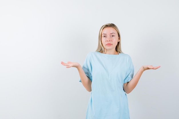 Junge Dame, die Skalengeste im T-Shirt macht und zögerlich isoliert aussieht