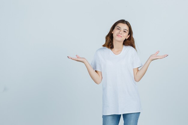 Junge Dame, die Skalengeste in T-Shirt, Jeans zeigt und selbstbewusst aussieht. Vorderansicht.