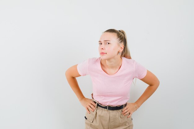 Junge Dame, die steht, um in T-Shirt und in Hosen klar zu hören und neugierig zu schauen