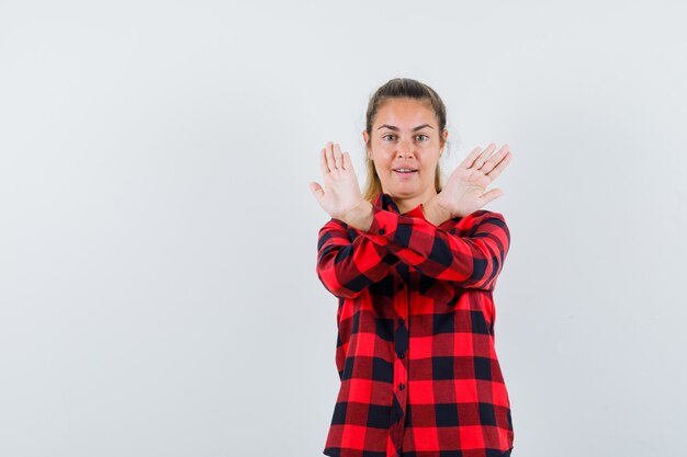 Junge Dame, die Stoppgeste im karierten Hemd zeigt und selbstbewusst aussieht