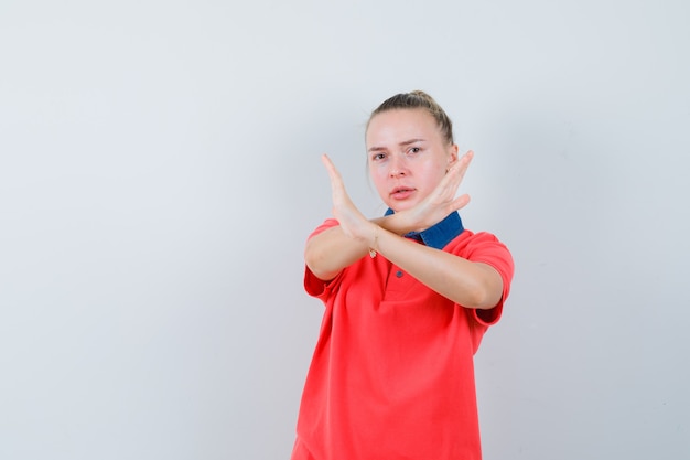 Kostenloses Foto junge dame, die stoppgeste im t-shirt zeigt und ernst schaut