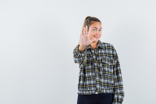 Junge Dame, die Stoppgeste in Hemd, Shorts zeigt und selbstbewusst, Vorderansicht schaut.