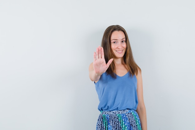 Junge Dame, die Stoppgeste in Unterhemd, Rock zeigt und froh aussieht