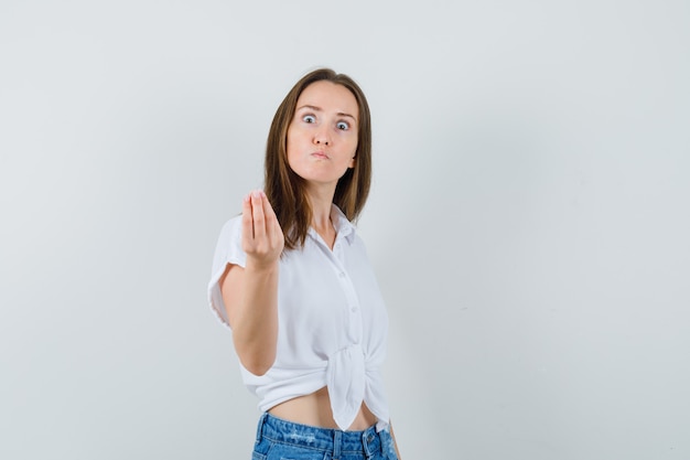 Junge Dame, die versucht, etwas in der weißen Bluse zu erklären und nervös aussieht. Vorderansicht.