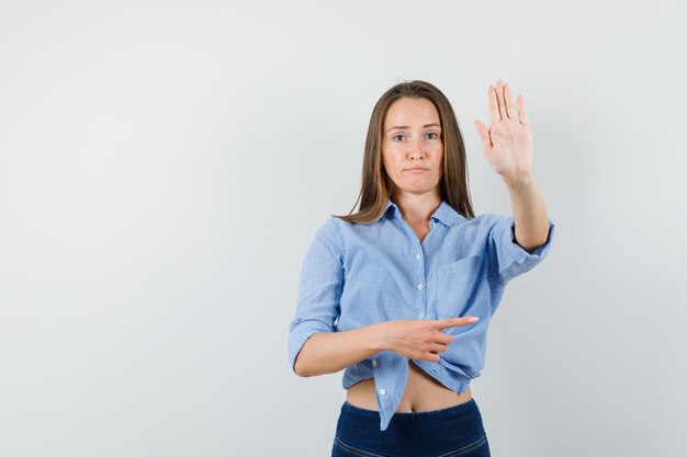 Junge Dame, die zur Seite zeigt und Stoppgeste im blauen Hemd zeigt