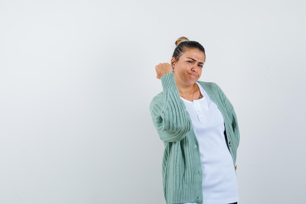 Junge Dame droht mit Faust in T-Shirt, Jacke und sieht selbstbewusst aus