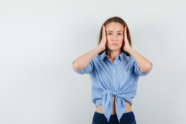 Junge Dame im blauen Hemd, Hosen, die Kopf mit Händen halten und erschöpft schauen