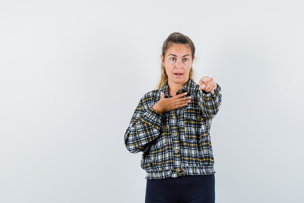 Junge Dame im Hemd, Shorts, die auf Kamera zeigen und zuversichtlich schauen, Vorderansicht.