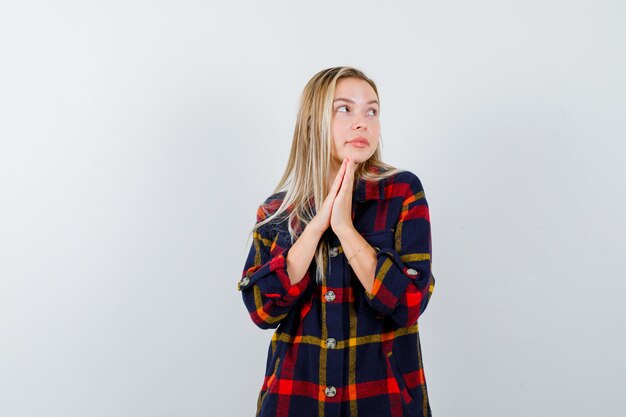 Junge Dame im karierten Hemd, das Finger zusammen drückt, um zu beten und friedlich, Vorderansicht zu schauen.