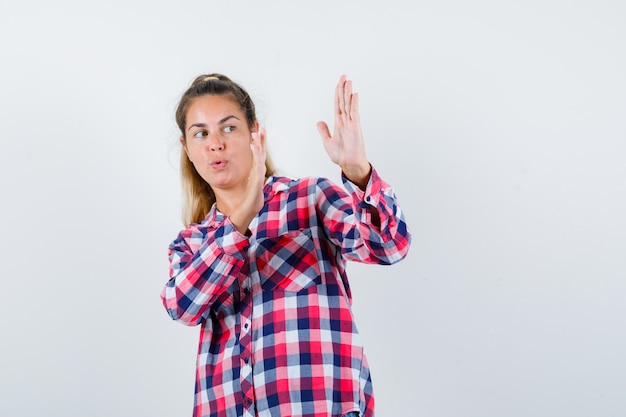 Junge Dame im karierten Hemd, das Karate-Hieb-Geste zeigt und kraftvolle Vorderansicht schaut.