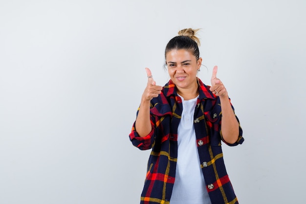 Junge dame im karierten hemd, das nach vorne zeigt und selbstbewusst aussieht