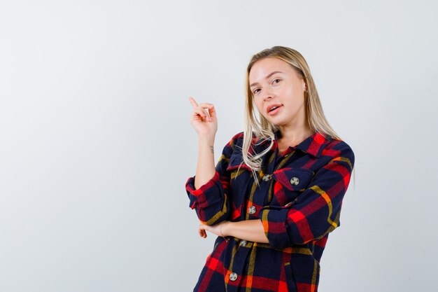 Junge Dame im karierten Hemd, das oben zeigt und glücklich schaut, Vorderansicht.