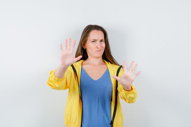 Junge Dame im T-Shirt, die Stoppgeste zeigt und verärgert aussieht, Vorderansicht.