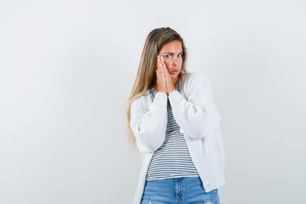 Junge Dame im T-Shirt, in der Jacke, in den Jeans, die Hände in der Gebetsgeste halten und ängstlich, Vorderansicht schauen.