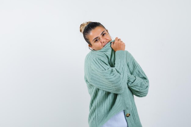 Junge Dame im T-Shirt, Jacke bedeckt den Mund mit Jacke und sieht süß aus