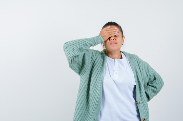 Junge Dame im T-Shirt, Jacke, die die Augen mit der Hand bedeckt und müde aussieht