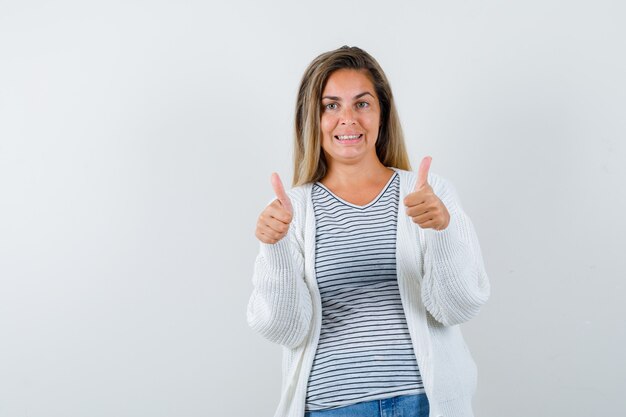 Junge Dame im T-Shirt, Jacke, die doppelte Daumen oben zeigt und fröhlich aussieht, Vorderansicht.